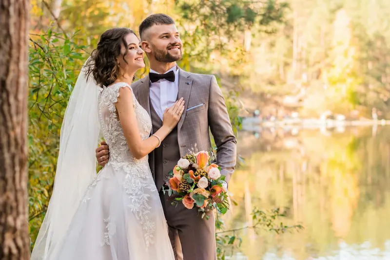 A newly married couple together beside a lake
