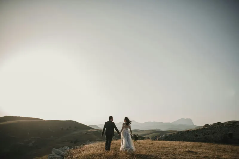 A couple walking together across hills in the evening light