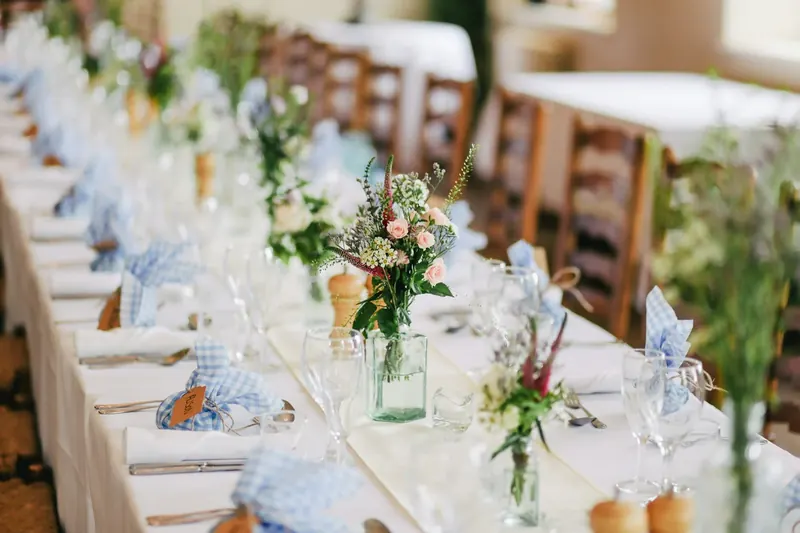 A long reception table set with flowers and soft blue napkins