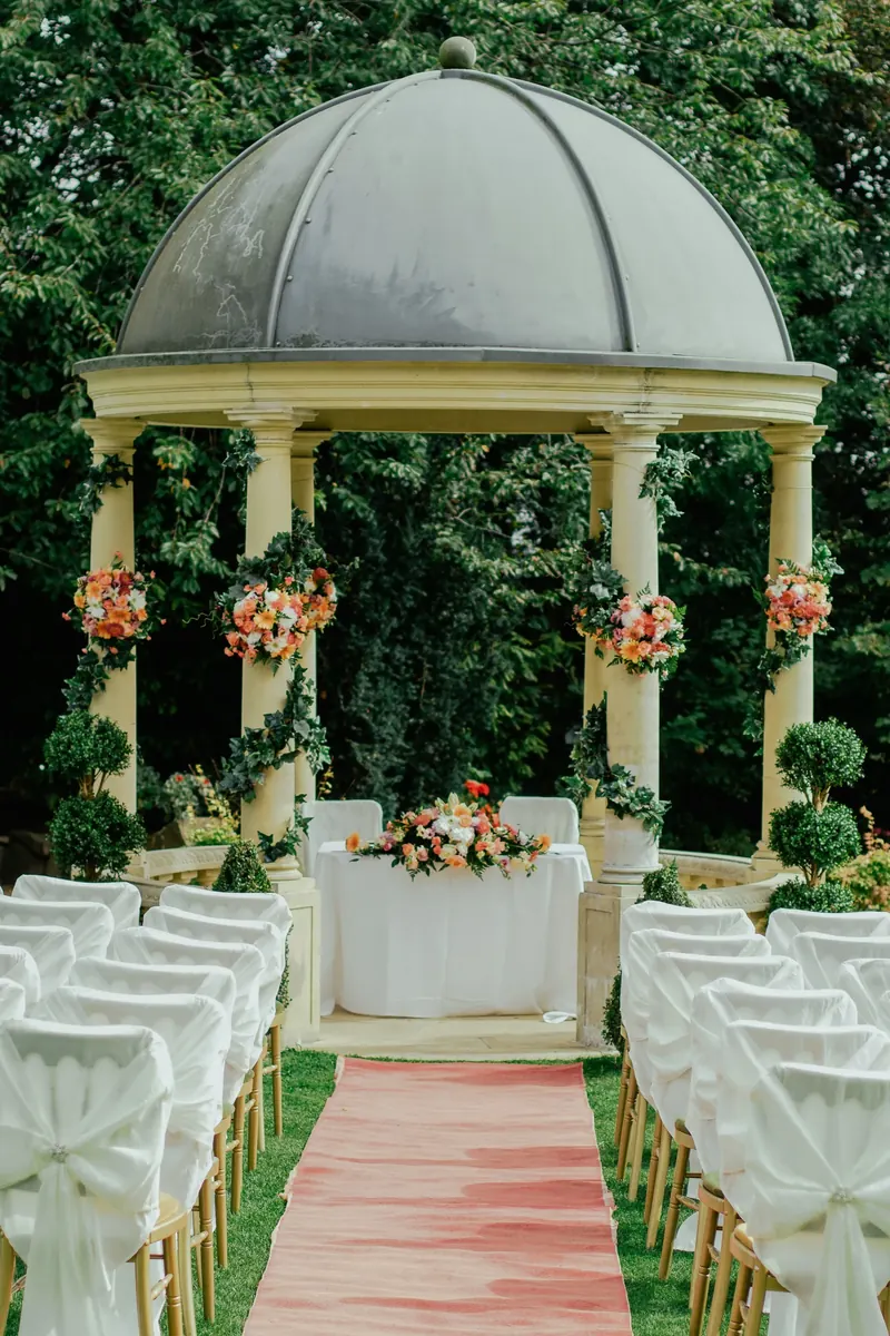 An intimate garden ceremony setting beneath a white gazebo