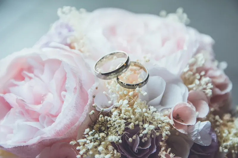 Wedding rings nestled in soft pink flowers